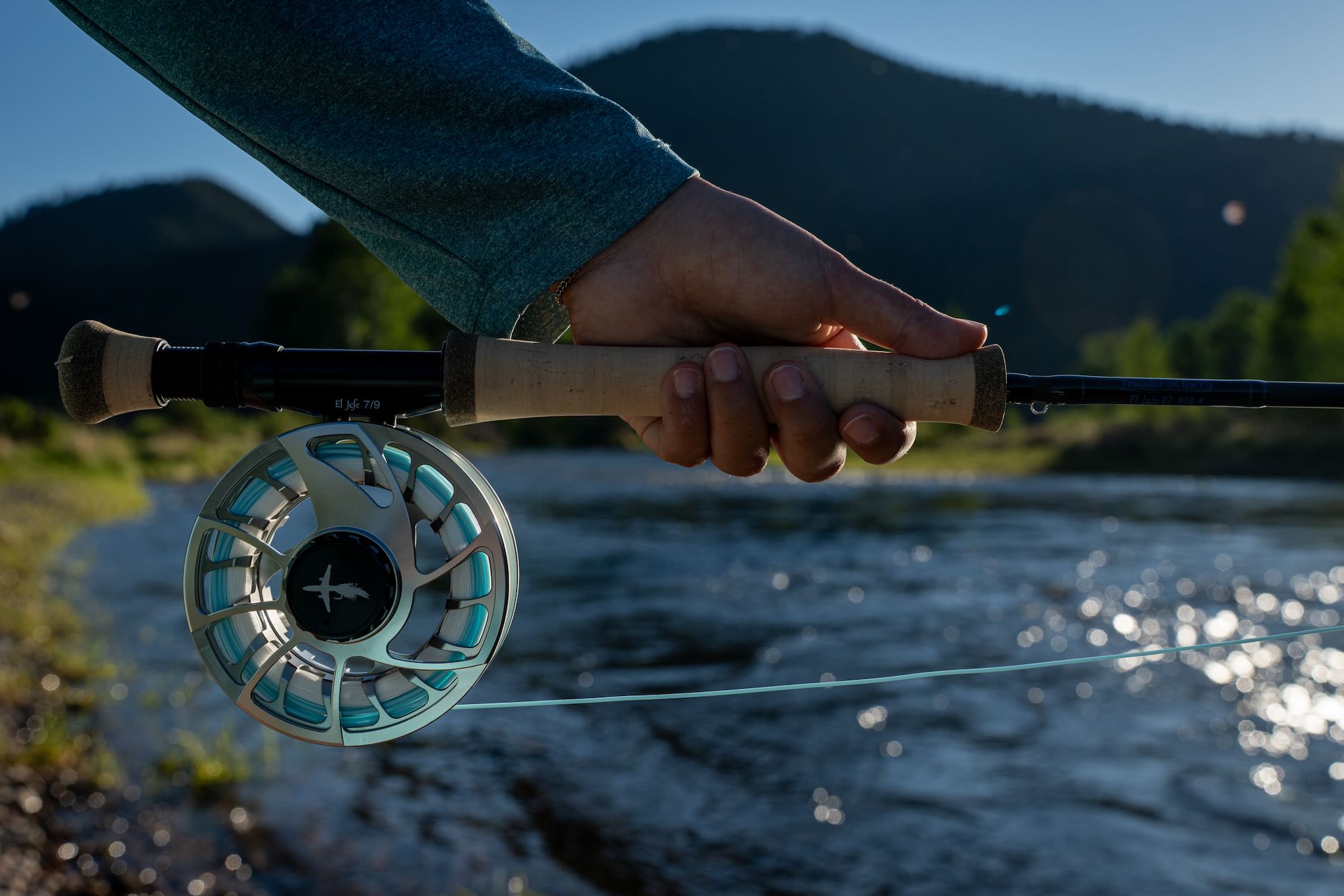 El Jefe v2 9-foot 8-weight fly rod paired with an El Jefe 7/8 reel, held streamside on a mountain river with fly line running out over the water
