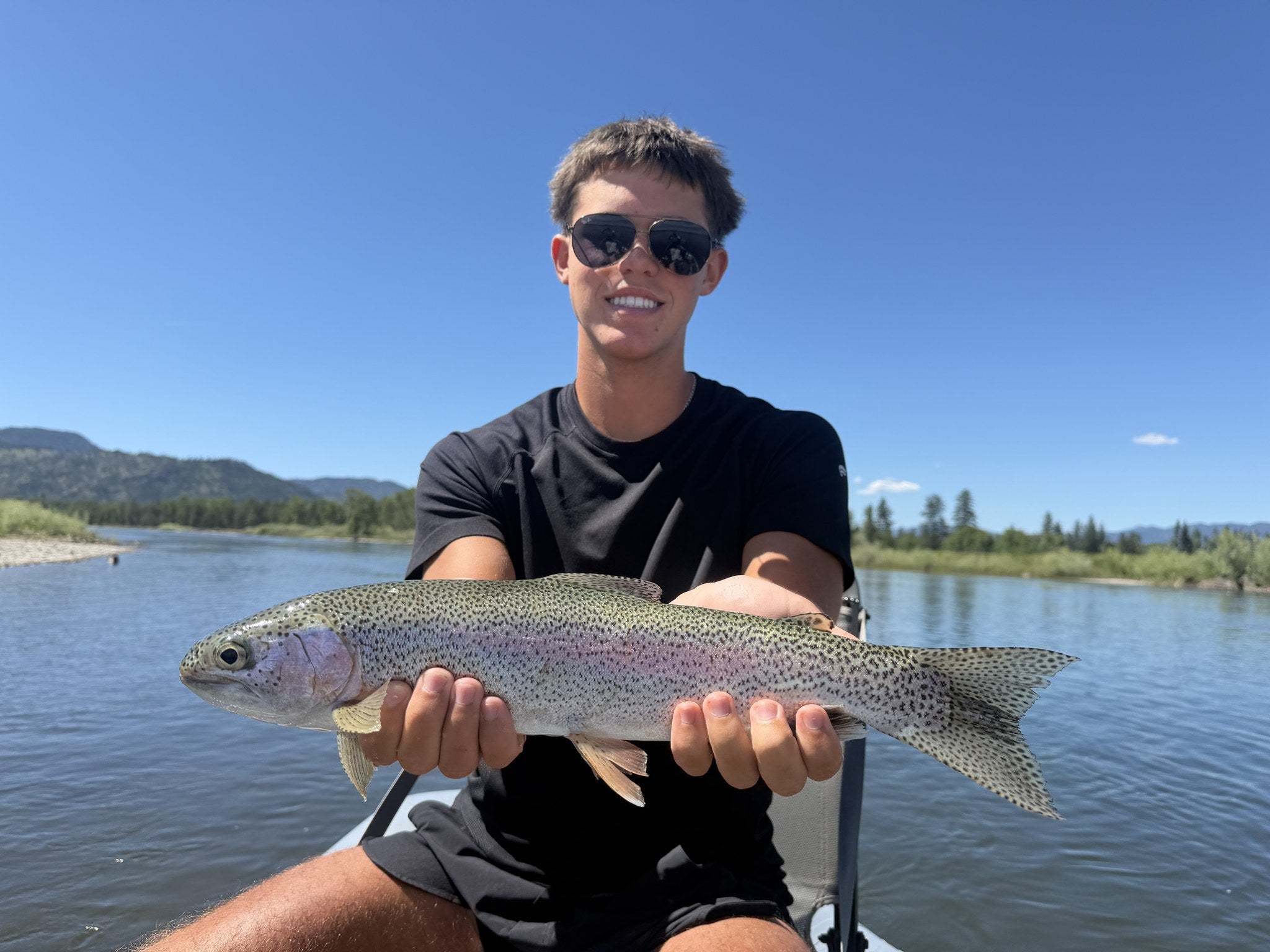 Angler holding a large rainbow trout on the Clark Fork River, Montana