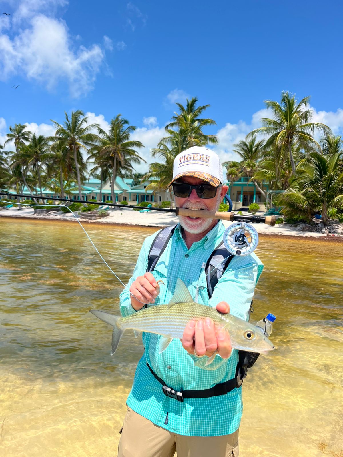 Angler Doug holding a bonefish — the first fish of a DIY saltwater grand slam — on the flats of Ambergris Caye, Belize