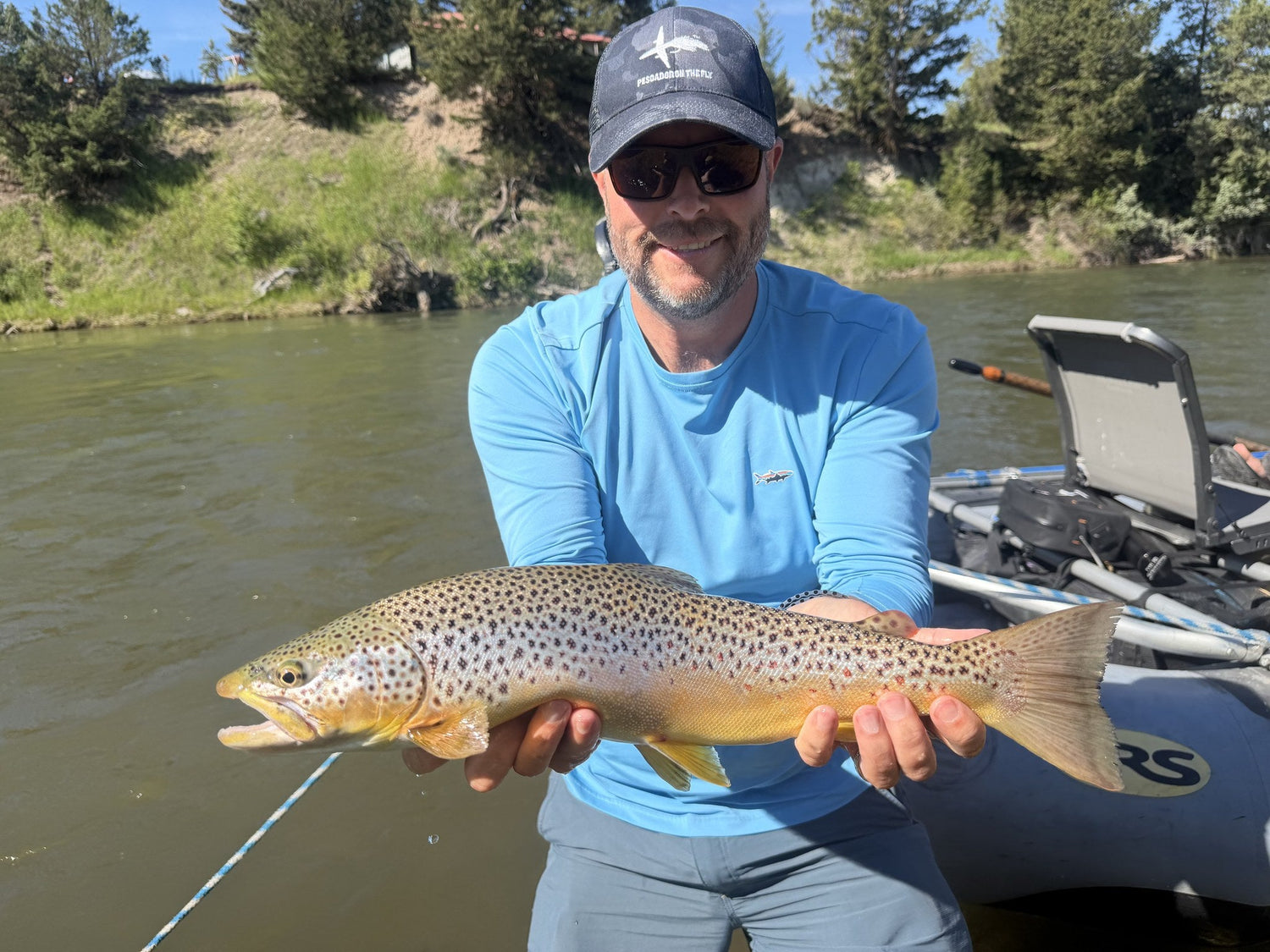 Angler holding a large brown trout from a drift boat on the Blackfoot, Montana